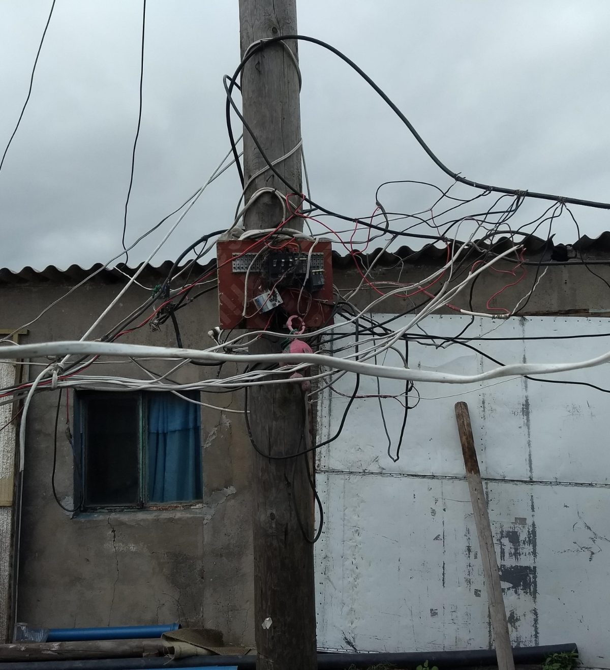 A wooden pole crowded with dozens of izinyokayoka illegal electrical connections feeding a settlement home.