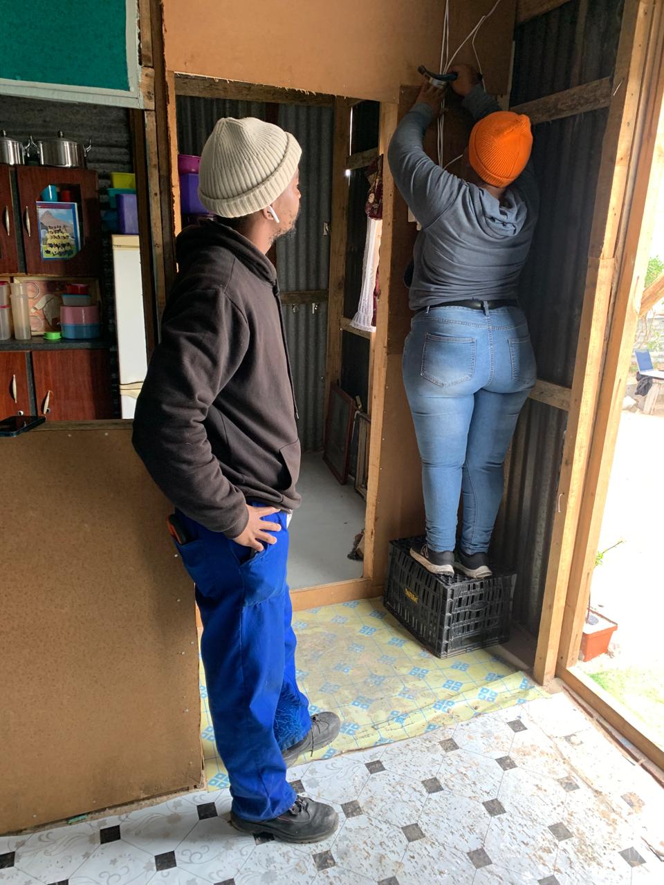 Two Zonke team members installing a meter inside a Cape Town settlement home.